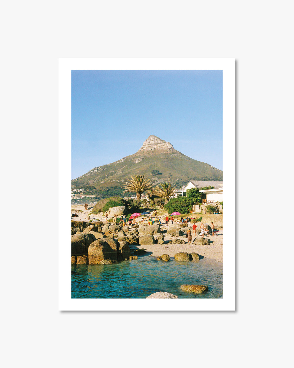 Beach scene with people, rocks, and a mountain in the background