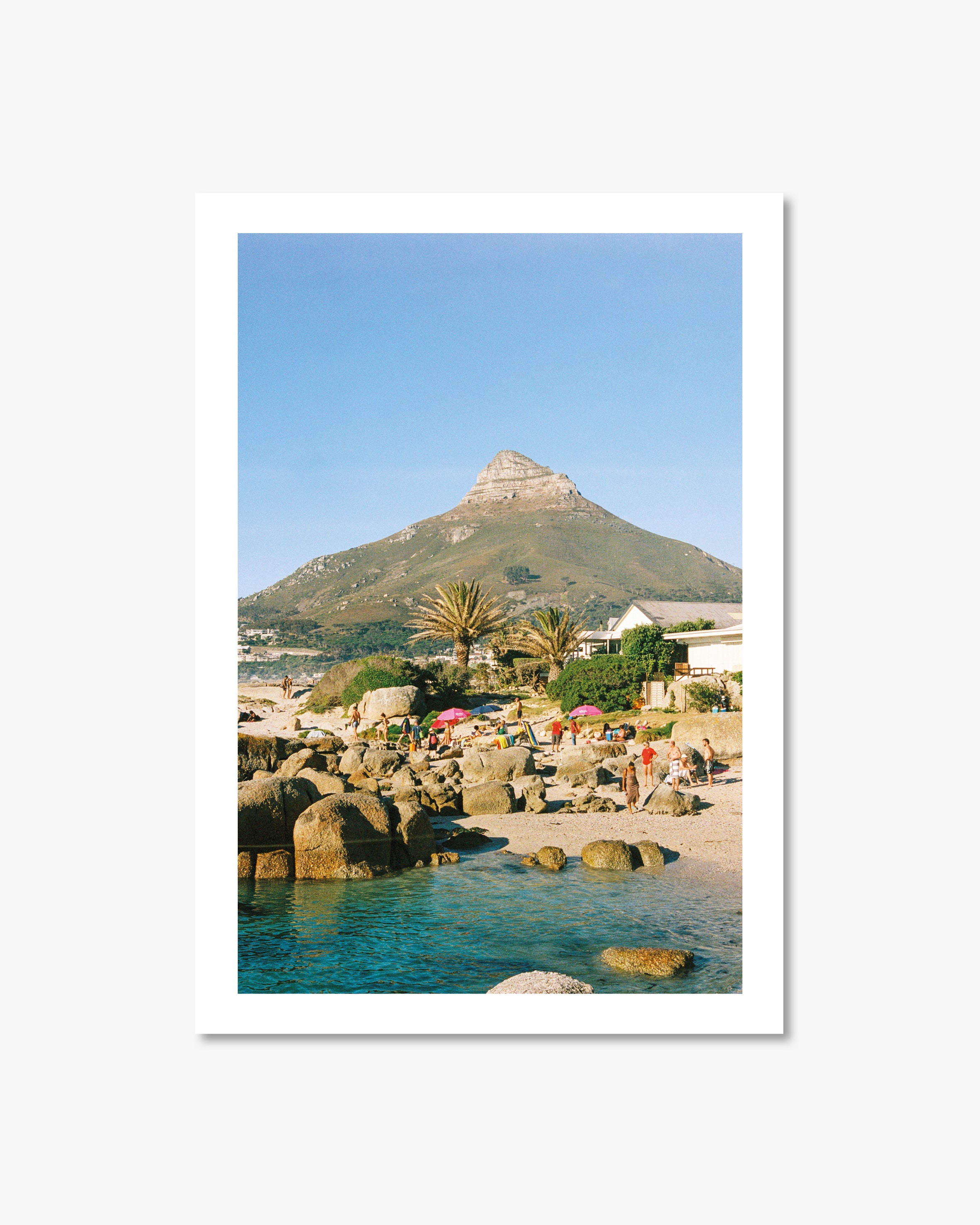 Beach scene with people, rocks, and a mountain in the background