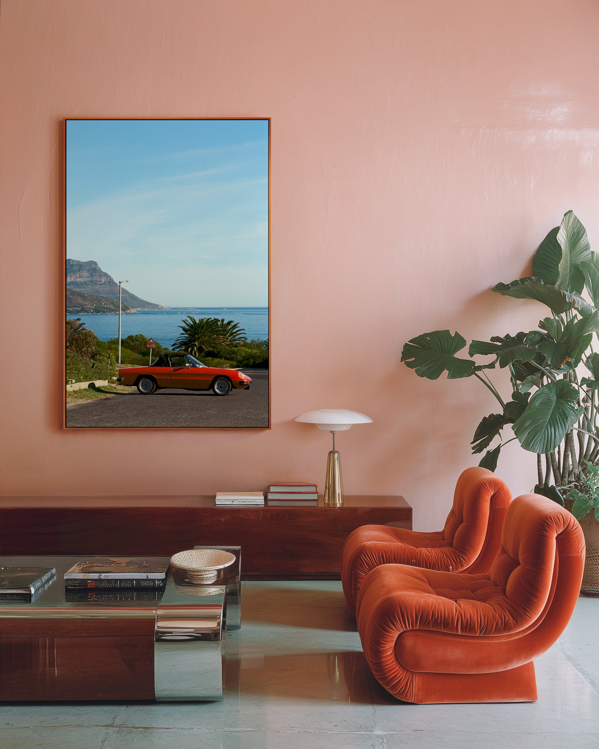 Modern living room with a pink wall, orange chair, and a framed picture of a car on a road.