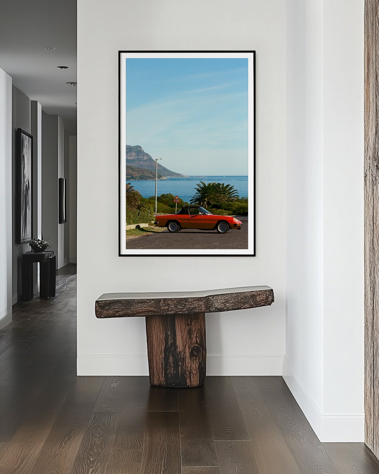 Framed artwork of a convertible car on a scenic road displayed in a modern interior setting.