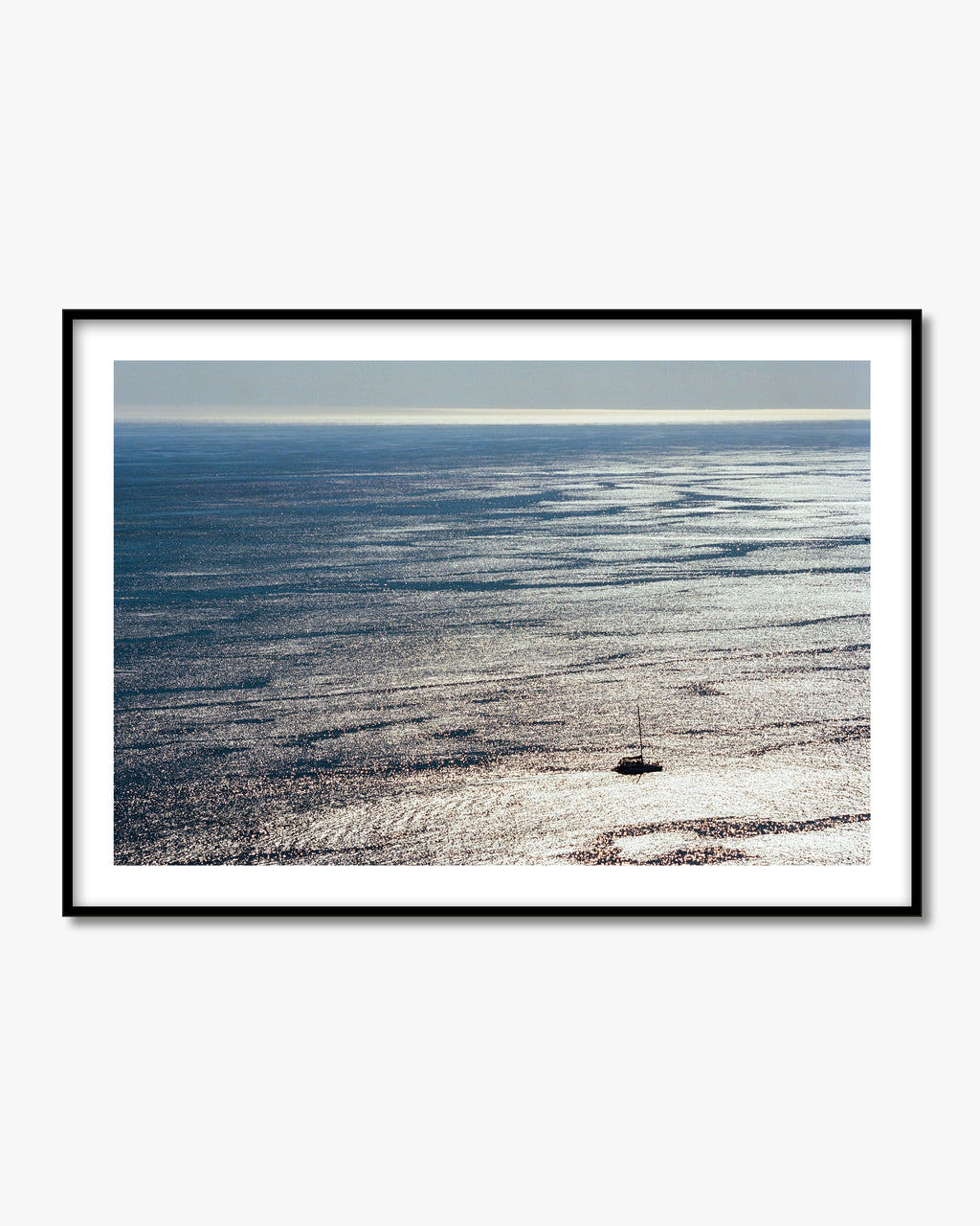 Framed photograph of a boat on a vast body of water with a clear sky.