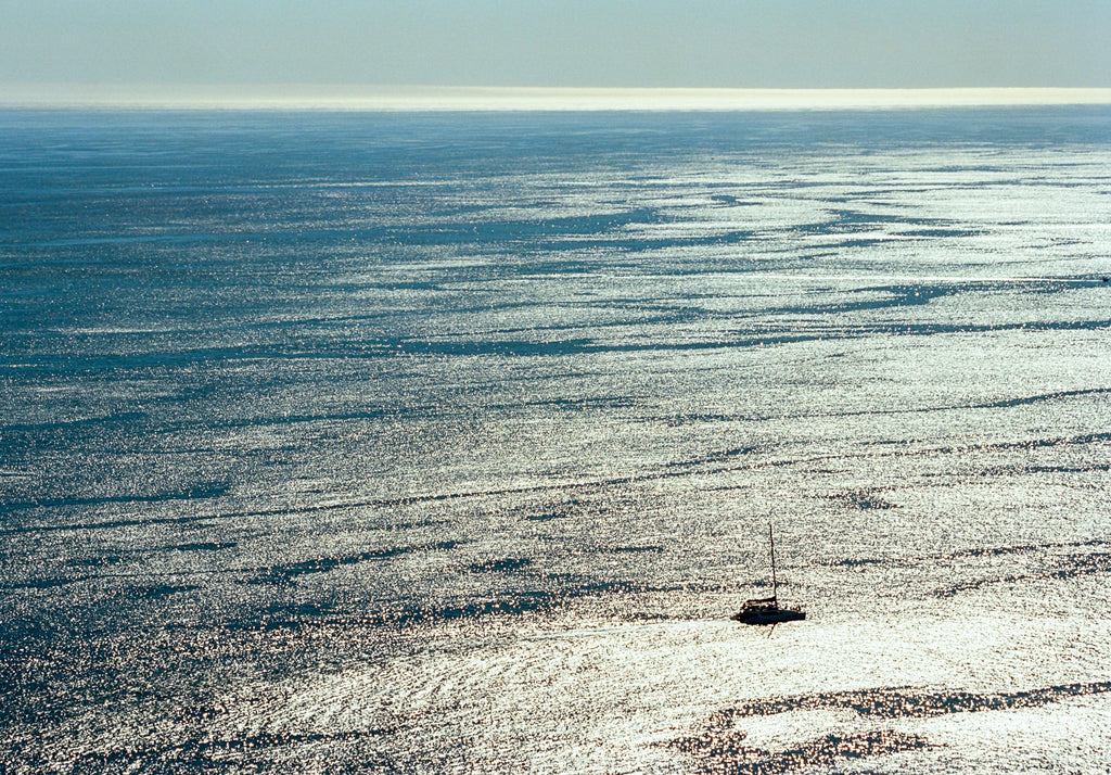 Small sailboat on a vast body of water under a clear sky
