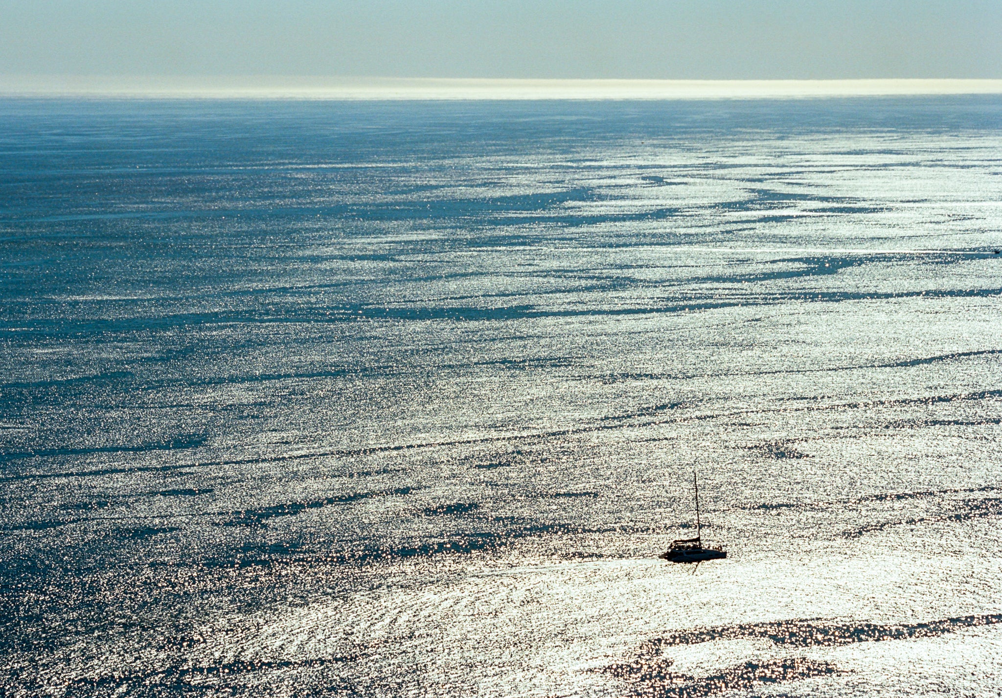 Small sailboat on a vast body of water under a clear sky