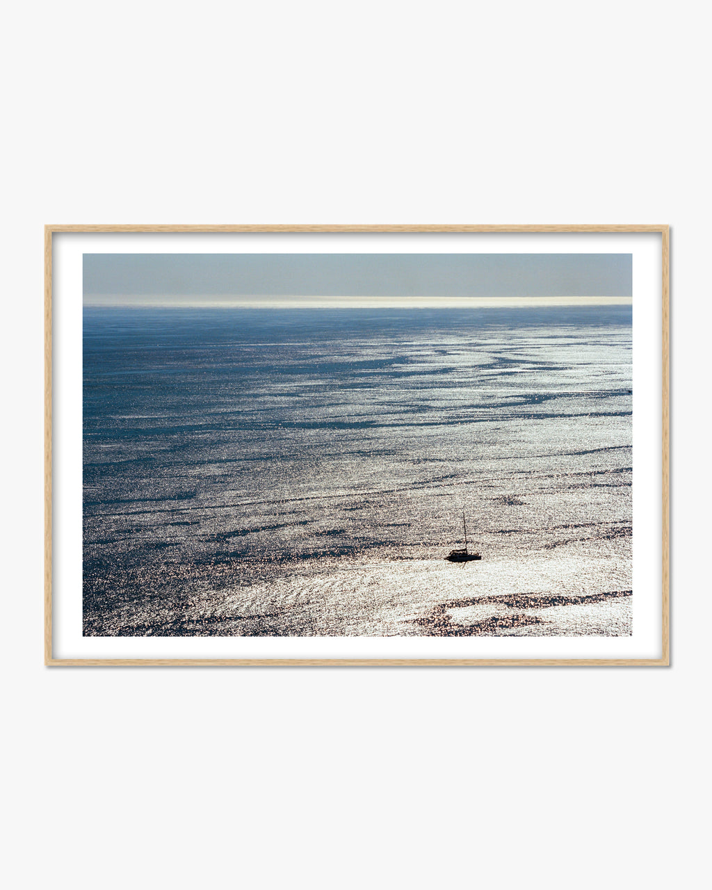 Framed photograph of a boat on a vast body of water with a clear sky.