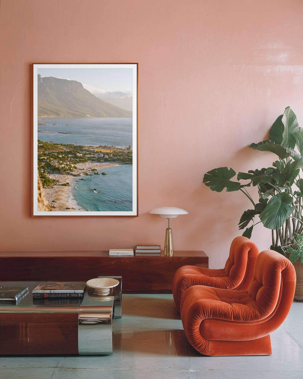 Modern living room with a pink wall, orange chair, and a scenic painting of a beach.
