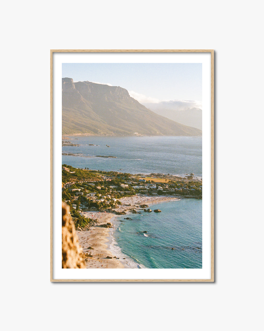 Framed artwork of a coastal landscape with mountains and turquoise water.