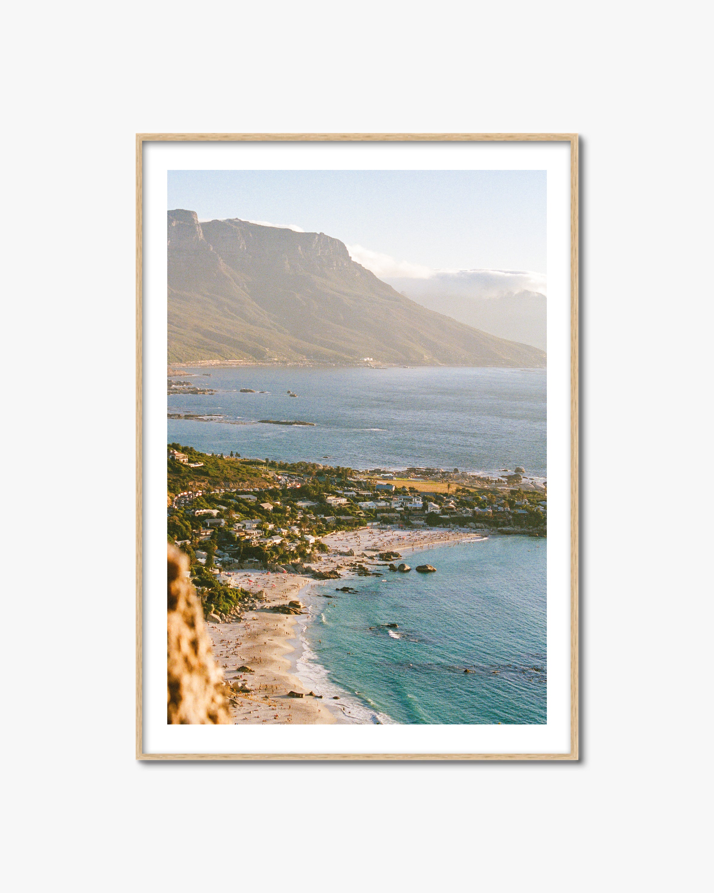 Framed artwork of a coastal landscape with mountains and turquoise water.