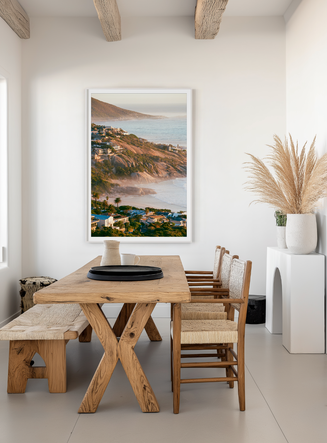 Dining area with wooden table and chairs, featuring a beach scene Photograph on the wall. By Sabine van Lagen