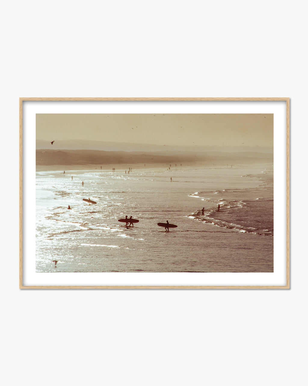 Framed photograph of surfers in the ocean with a beach in the background