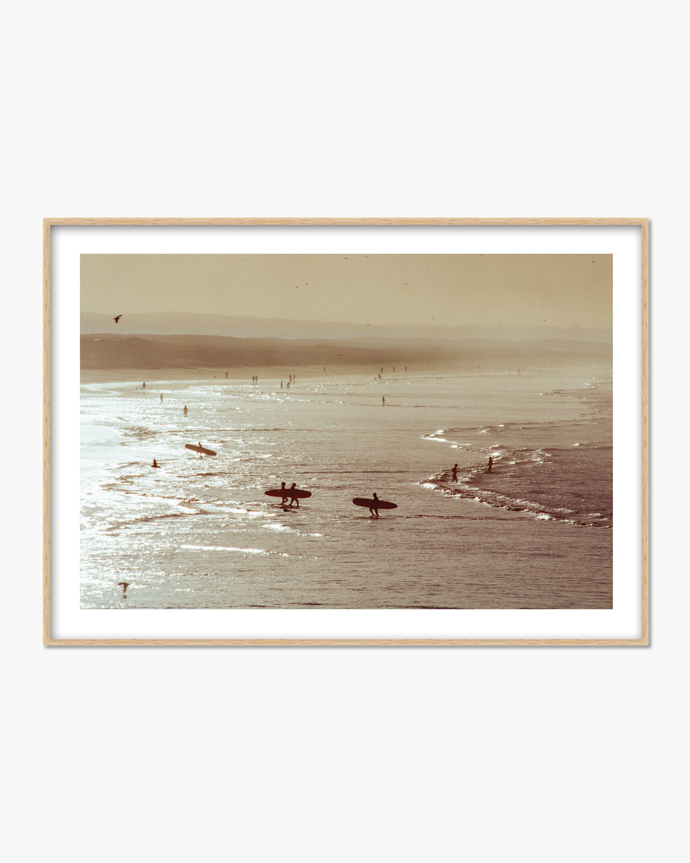 Framed photograph of surfers in the ocean with a beach in the background